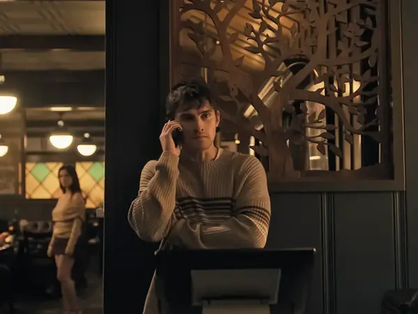 Bear on his phone with Nikki in the background, illustrating the film’s theme of obsession.