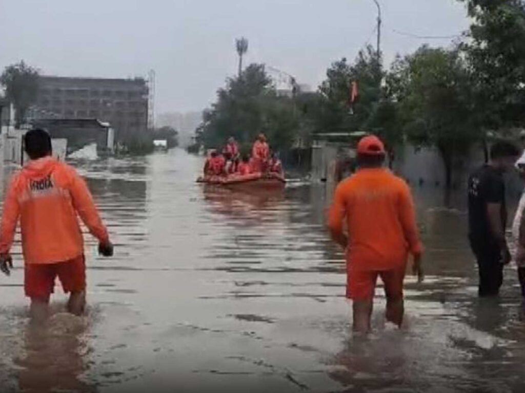 NDRF workforce wading through floodwaters during a rescue operation.