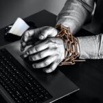 Shackled hands forced into cyber slavery.