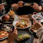 A group of people photographing food, illustrating the trend of eating for content.