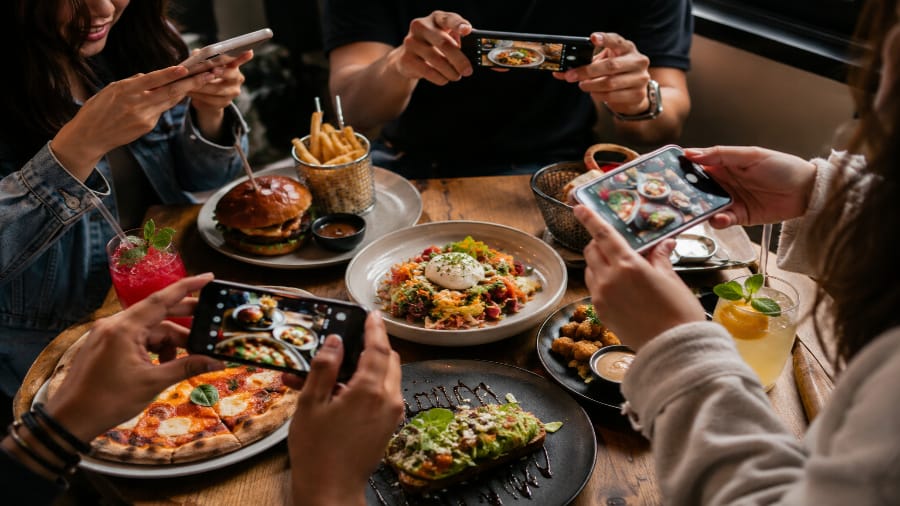 A group of people photographing food, illustrating the trend of eating for content.